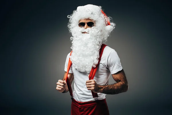 Weihnachtsmann mit Sonnenbrille steht isoliert auf grauem Hintergrund — Stockfoto