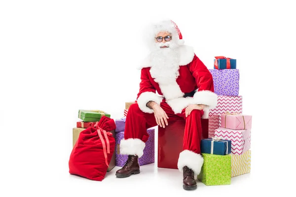 Pensativo santa claus sentado en la pila de cajas de regalo aislado sobre fondo blanco — Stock Photo