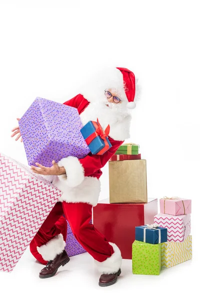 Santa claus en gafas colgando pila de cajas de regalo aisladas sobre fondo blanco - foto de stock