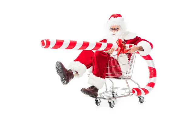 Santa claus tenant grand bâton de Noël rayé dans un chariot isolé sur fond blanc — Photo de stock