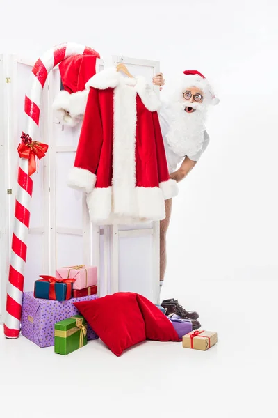 Shocked santa claus without costume looking out from folding screen isolated on white background — Stock Photo