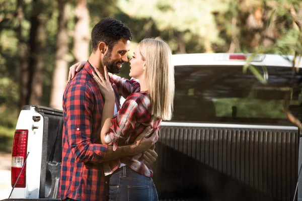 Seitenansicht eines glücklichen jungen Paares, das sich in der Nähe von Pick-up-Auto im Freien ansieht — Stockfoto