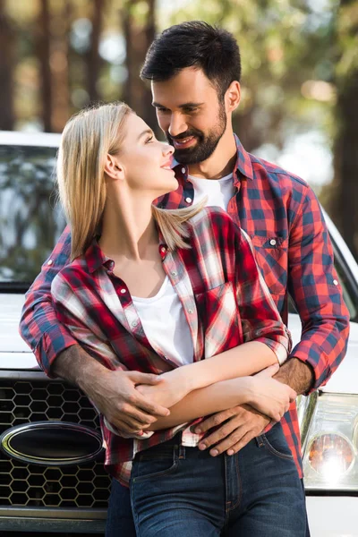 Молодая пара обнимает друг друга рядом подобрать автомобиль на открытом воздухе — стоковое фото
