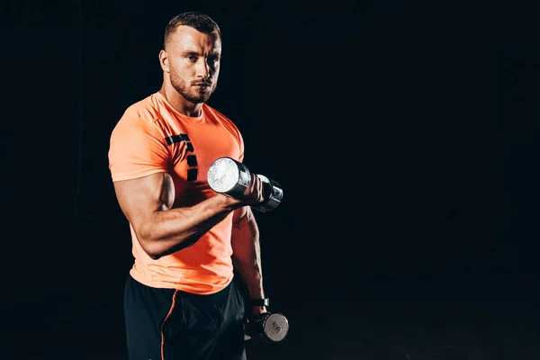Handsome fit sportsman working out with barbells in dark gym — Stock Photo