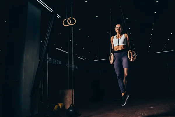 Attractive athletic sportswoman working out with gymnastic rings — Stock Photo