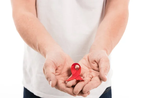 Cropped shot of man in blank white t-shirt holding aids awareness red ribbon isolated on white — Stock Photo