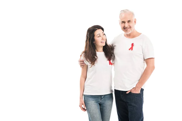 Sorridente adulto interracial casal em branco t-shirts com aids consciência vermelho fitas abraçando isolado no branco — Fotografia de Stock