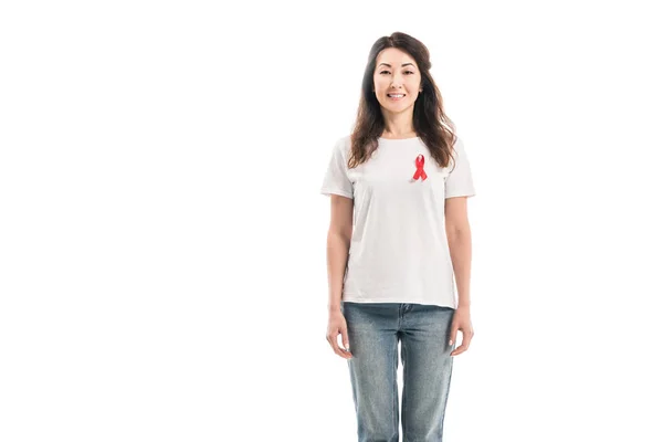 Adult asian woman with aids awareness red ribbon on t-shirt looking at camera isolated on white — Stock Photo