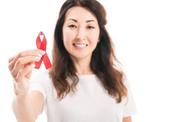 Close-up portrait of happy adult asian woman holding aids awareness red ribbon isolated on white — Stock Photo