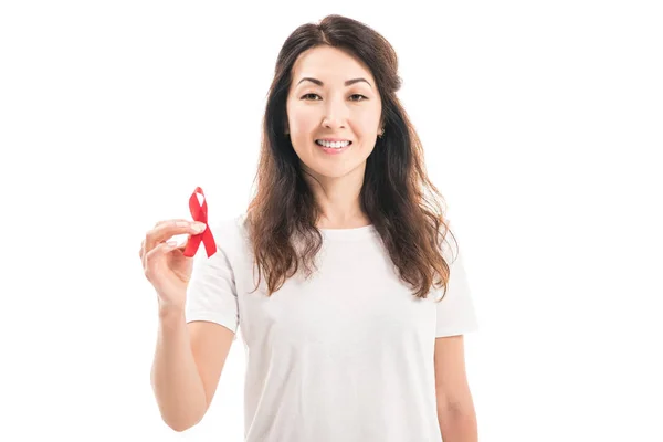 Smiling adult asian woman holding aids awareness red ribbon isolated on white — Stock Photo