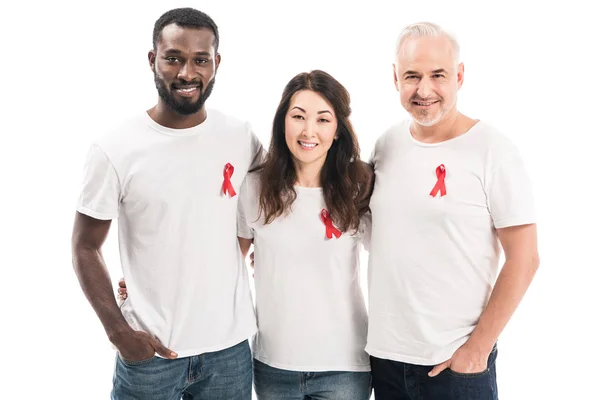 Multiethnische Gruppe von Menschen in weißen T-Shirts mit Hilfsmitteln Bewusstsein rote Bänder umarmen und schauen in die Kamera isoliert auf weiß — Stockfoto
