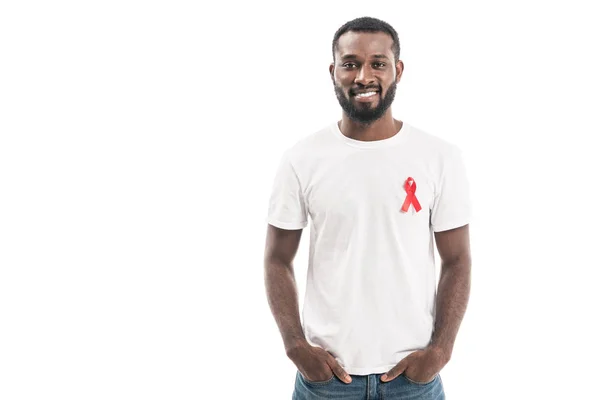 Glücklich schöner Mann im weißen T-Shirt mit Hilfsmitteln Bewusstsein rote Schleife Blick in die Kamera isoliert auf weiß — Stockfoto