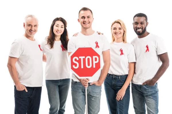 Groupe de personnes en t-shirts blancs vierges avec des rubans rouges sensibilisation sida et stop panneau de signalisation en regardant la caméra isolée sur blanc — Photo de stock