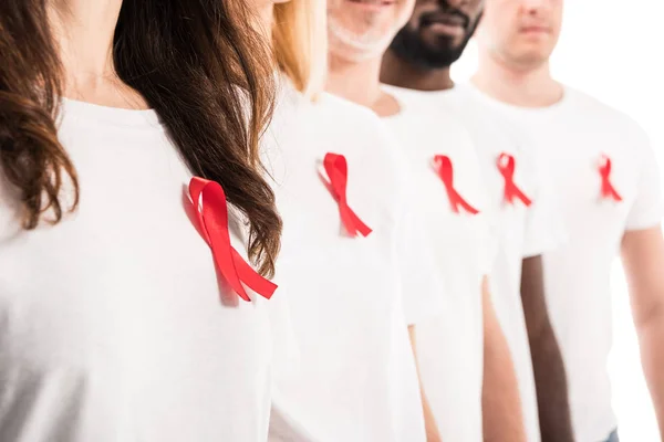 Cropped shot of group of people in blank white t-shirts standing in row with aids awareness red ribbons isolated on white — Stock Photo