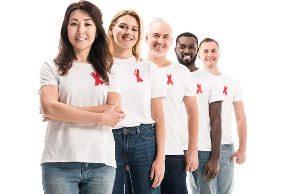 Happy group of people in blank white t-shirts standing in row with aids awareness red ribbons isolated on white — Stock Photo