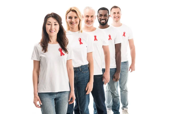 Gruppo sorridente di persone in bianco bianco t-shirt in piedi in fila con aiuti consapevolezza nastri rossi isolati su bianco — Foto stock