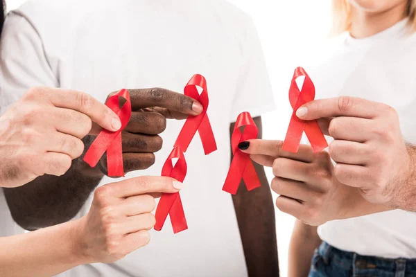 Recortado tiro de personas en blanco blanco camisetas sosteniendo ayudas conocimiento cintas rojas - foto de stock