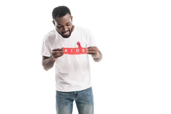 Homem americano africano em branco camiseta branca com aids consciência fita vermelha e blocos com letras AIDS isolado em branco — Fotografia de Stock