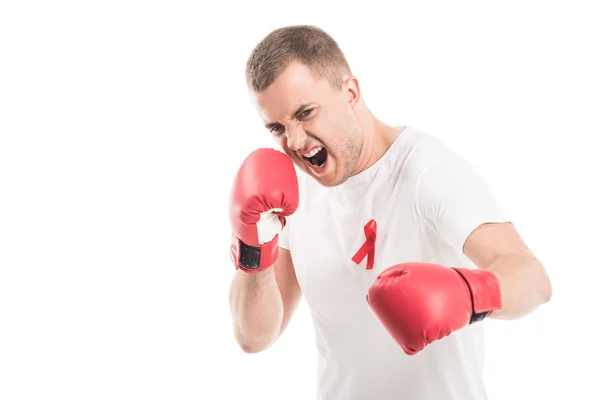 Angry handsome man in blank white t-shirt with aids awareness red ribbon and boxing gloves isolated on white, fighting aids concept — Stock Photo