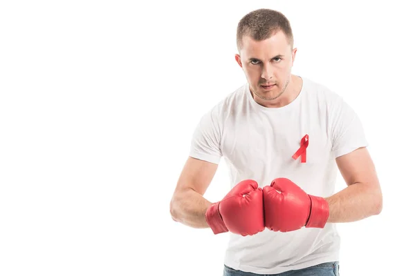 Homme beau et sérieux en t-shirt blanc vierge avec des gants de boxe et un ruban rouge de sensibilisation au sida isolé sur du blanc, concept d'aide au combat — Photo de stock