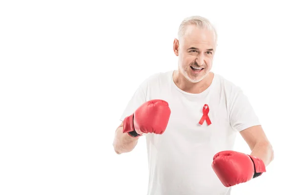 Emotional mature man in blank white t-shirt with aids awareness red ribbon and boxing gloves isolated on white, fighting aids concept — Stock Photo