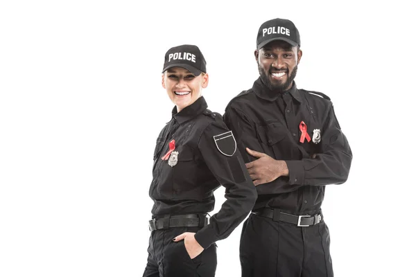 Confident police officers with aids awareness red ribbons looking at camera isolated on white — Stock Photo