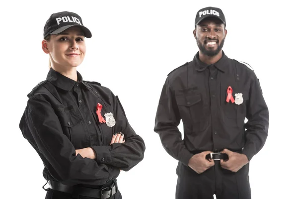 Oficiales de policía felices con cintas rojas de conciencia de sida mirando a la cámara aislada en blanco - foto de stock
