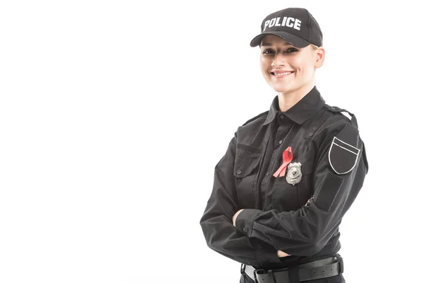 Feliz oficial de policía mujer con SIDA cinta roja de conciencia mirando a la cámara con los brazos cruzados aislados en blanco - foto de stock