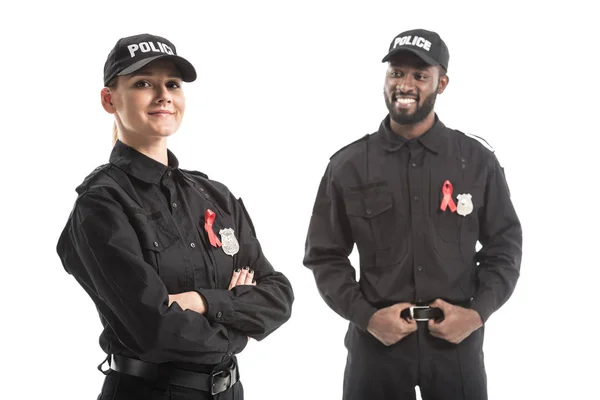 Agentes de policía sonrientes con cintas rojas de conciencia SIDA aislados en blanco - foto de stock