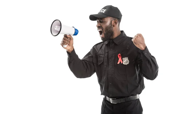 Angry african american police officer with aids awareness red ribbon shouting with megaphone isolated on white — Stock Photo