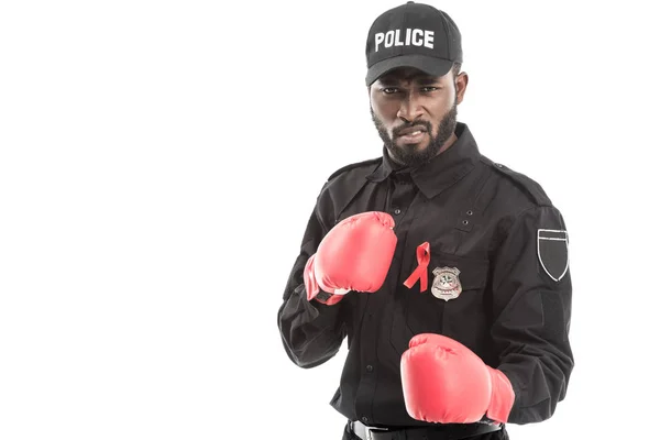 Grimacing african american police officer with boxing gloves isolated on white, fighting aids concept — Stock Photo