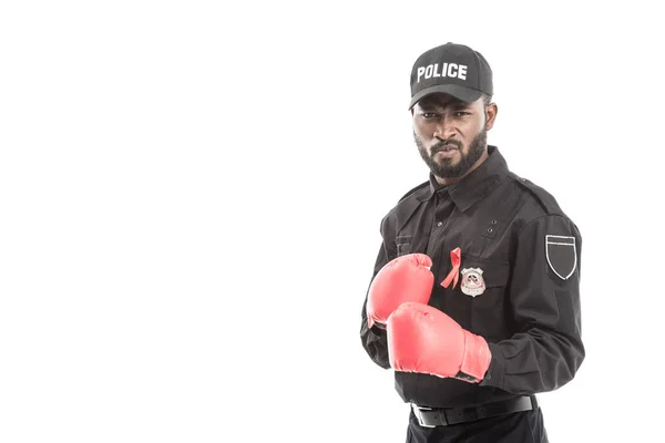 Oficial de policía afroamericano serio con guantes de boxeo aislados en blanco, concepto de sida de lucha - foto de stock