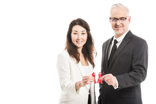 Multiethnic adult businesspeople holding aids awareness red ribbons isolated on white — Stock Photo
