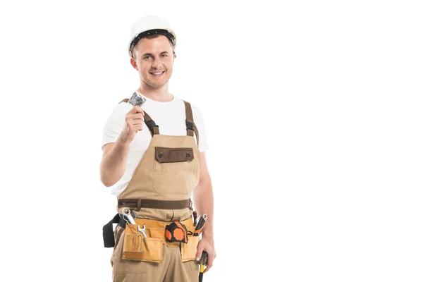 Handsome adult builder holding condom and looking at camera isolated on white — Stock Photo