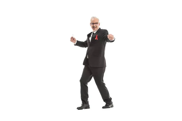 Funny mature businessman in suit with aids awareness red ribbon dancing isolated on white — Stock Photo