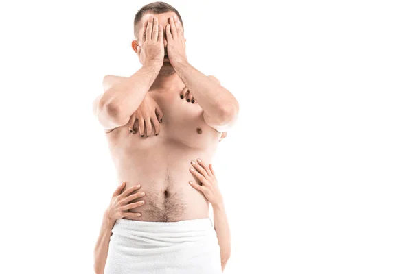 Hombre sin camisa que cubre la cara con las manos, mientras que las manos femeninas que lo tocan por detrás aislado en blanco, SIDA concepto - foto de stock