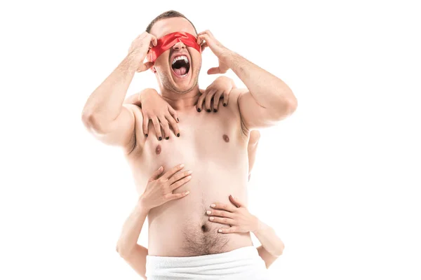 Screaming shirtless man with tied eyes and female hands touching him from behind isolated on white, aids concept — Stock Photo