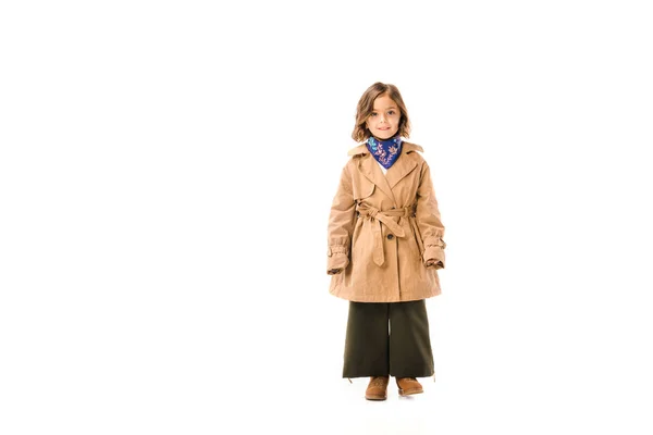 Linda criança no casaco de trincheira de pé e olhando para a câmera isolada no branco — Fotografia de Stock