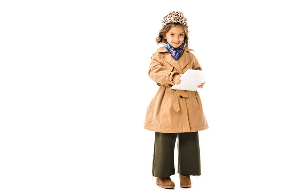 Adorable petit enfant en trench coat en utilisant la tablette et en regardant la caméra isolée sur blanc — Photo de stock