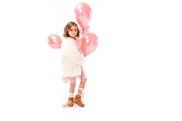 Hermoso niño con estilo en abrigo de piel con globos de aire de color rosa aislado en blanco - foto de stock