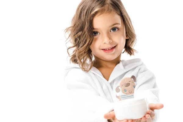 Cute kid in white bathrobe showing body cream in hands isolated on white — Stock Photo