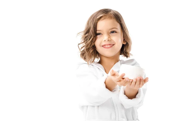 Lindo niño en blanco albornoz mostrando crema corporal en manos aisladas en blanco - foto de stock
