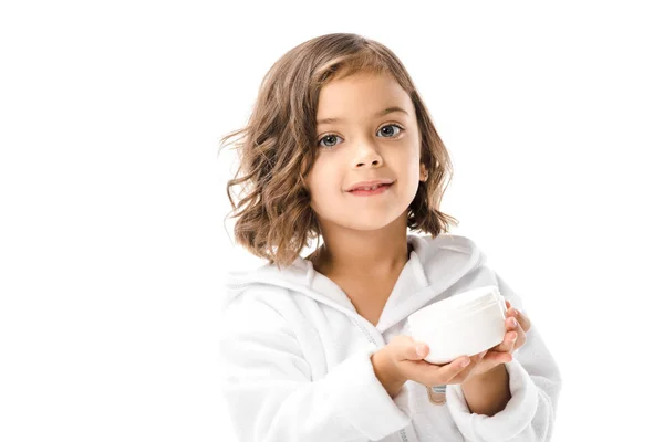 Niedliches Kind im weißen Bademantel zeigt Körpercreme in den Händen isoliert auf weiß — Stockfoto