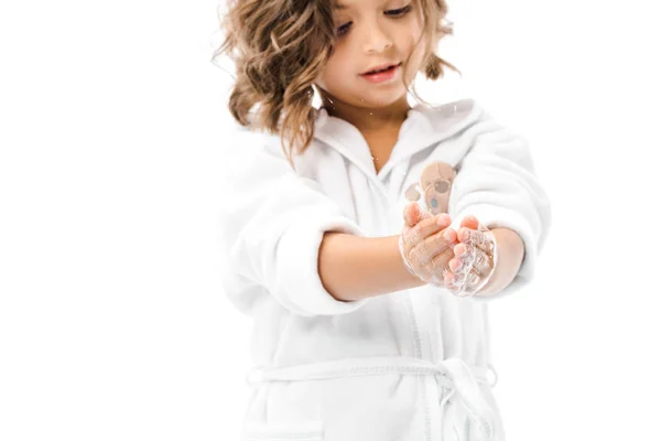 Маленька дитина в халаті миє руки з милом ізольовано на білому — стокове фото