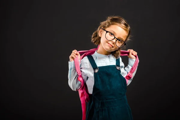 Porträt der entzückenden Schülerin mit Brille und Rucksack isoliert auf schwarz — Stockfoto