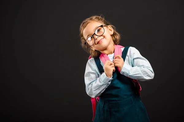 Retrato de criança adorável em idade escolar em óculos com mochila isolada em preto — Fotografia de Stock