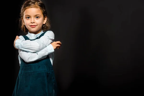 Porträt eines süßen Schulkindes, das isoliert auf schwarz in die Kamera blickt — Stockfoto