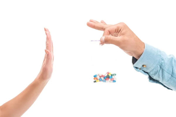 Imagen recortada de chica rechazando píldoras de drogas poco saludables y mostrando señal de stop al hombre aislado en blanco - foto de stock