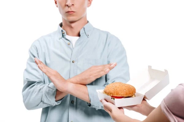 Imagen recortada del hombre que no muestra ningún signo a la mujer proponiendo hamburguesa aislada en blanco - foto de stock