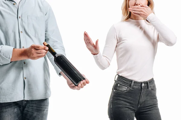 Abgeschnittenes Bild einer Frau, die den Mund bedeckt und eine Flasche Rotwein auf weißem Grund ablehnt — Stockfoto